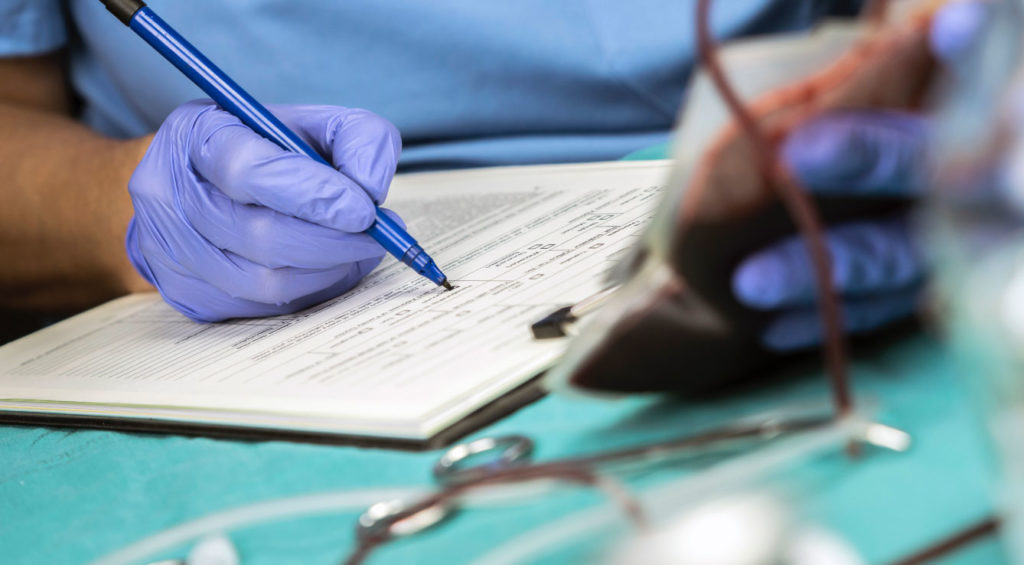 nurse writes down blood transfusion data in a hospital